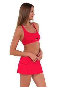Side pose #1 of Daria wearing Sunsets Geranium Sporty Swim Skirt with matching Brandi Bralette bikini top