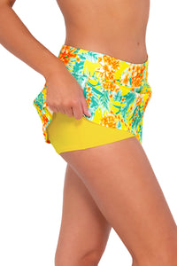 Side pose #1 of Daria wearing Sunsets Golden Tropics Sandbar Rib Sporty Swim Skirt lifted to show attached swim short
