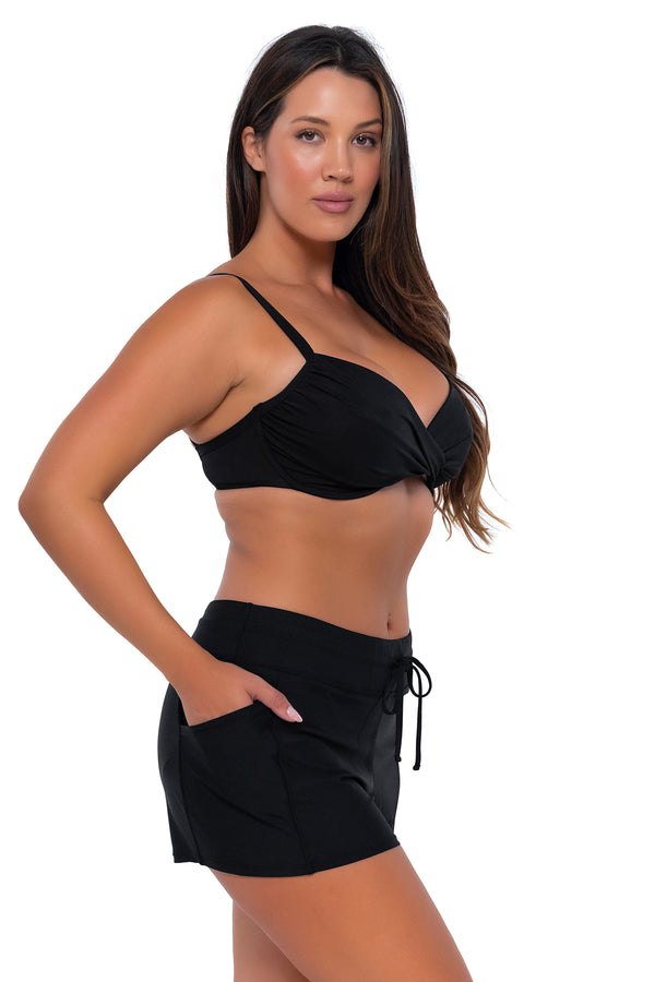 Side pose #1 of Nicky wearing Sunsets Escape Black Laguna Swim Short with matching Crossroads Underwire bikini top
