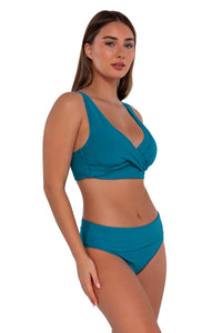 Side pose #1 of Taylor wearing Sunsets Avalon Teal Hannah High Waist Bottom showing folded waist paired with Elsie Top bikini bralette