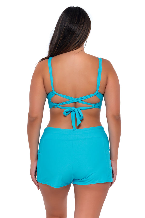 Back pose #1 of Nicky wearing Sunsets Escape Blue Bliss Laguna Swim Short with matching Elsie Top underwire bikini