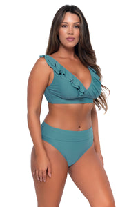 Side pose #1 of Nicky wearing Sunsets Ocean Willa Wireless Top with matching Hannah High Waist bikini bottom showing folded waist