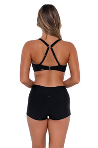 Back pose #1 of Taylor wearing Sunsets Black Taylor Bralette Top showing crossback straps with matching Kinsley Swim Short