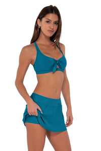 Side pose #1 of Gigi wearing Sunsets Avalon Teal Sporty Swim Skirt paired with Brandi Bralette bikini top