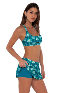 Side pose #1 of Gigi wearing Sunsets Palm Beach Sporty Swim Skirt paired with Brandi Bralette bikini top