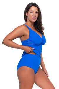 Side pose #1 of Nicky wearing Sunsets Electric Blue Forever Tankini Top lifted up to show matching Hannah High Waist bikini bottom