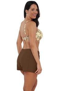 Oblique pose #1 of Nicki wearing Sunsets Escape Tiki Brown Laguna Swim Short paired with matching