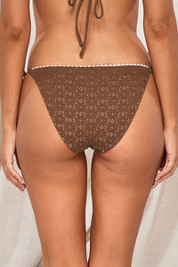 Back pose #1 of Jessica wearing Swim Systems Cocoa Daisy Eyelet Pom Pom Tie Side Bottom