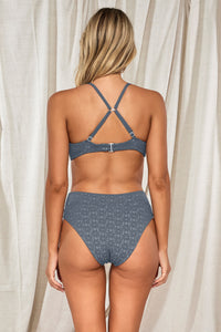 Back pose #1 of Jessica wearing Swim Systems Dusk Daisy Eyelet Pom Pom Annalee Underwire Top showing crossback straps paired with matching Delfina V Front Bottom