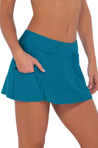 Side pose #1 of Gigi wearing Sunsets Avalon Teal Sporty Swim Skirt with hand in pocket