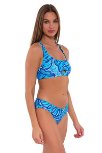 Side pose #1 of Daria wearing Sunsets Seaside Vista Brandi Bralette Top with matching Alana Reversible Hipster bikini bottom